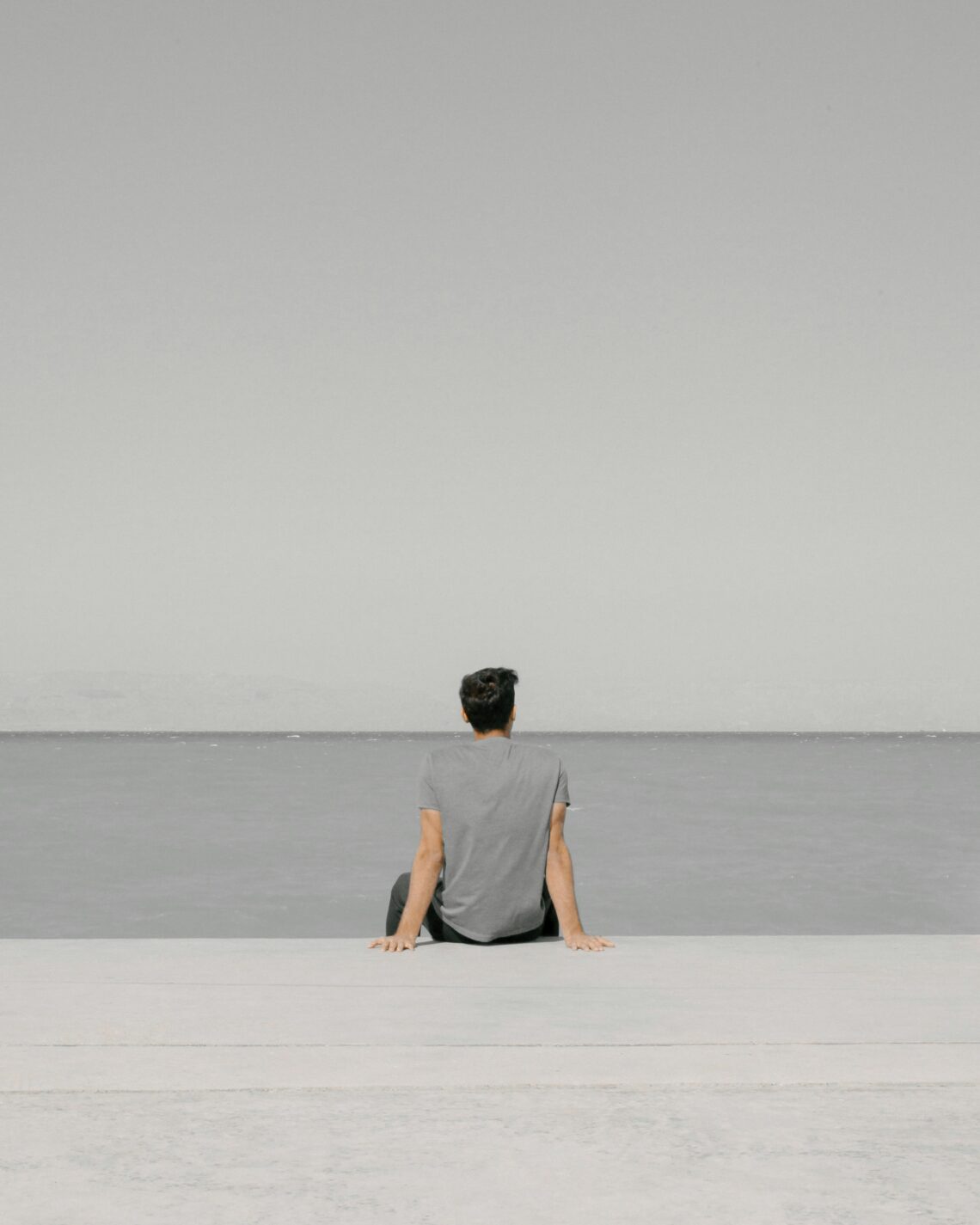 Mężczyzna siedzący samotnie nad wodą, symbolizujący stres i potrzebę wyciszenia