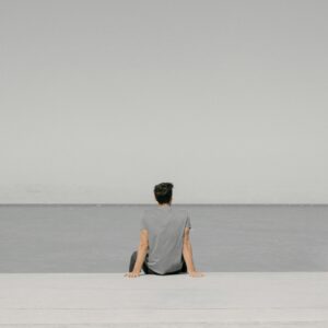 Mężczyzna siedzący samotnie nad wodą, symbolizujący stres i potrzebę wyciszenia