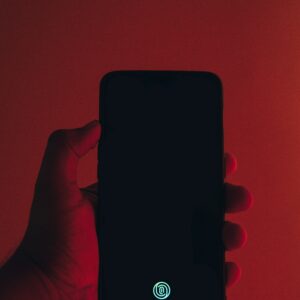 Telefon w dłoni, rozświetlony czerwienią – symbol uzależnienia i kontroli
