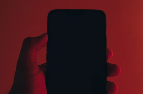 Telefon w dłoni, rozświetlony czerwienią – symbol uzależnienia i kontroli