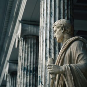 Starożytna marmurowa statua filozofa wśród kolumn – symboliczne nawiązanie do początków minimalizmu i jego filozoficznych korzeni