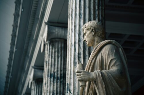 Starożytna marmurowa statua filozofa wśród kolumn – symboliczne nawiązanie do początków minimalizmu i jego filozoficznych korzeni