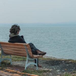 Osoba siedząca samotnie na ławce nad wodą – symboliczny moment nicnierobienia i refleksji