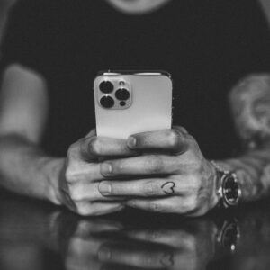 Mężczyzna trzymający smartfon w dłoniach – obraz przeciążenia bodźcami, które prowadzą do potrzeby postu dopaminowego.