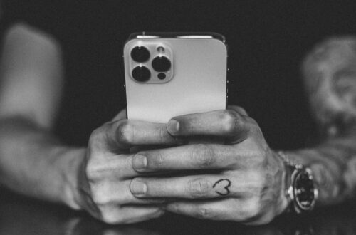 Mężczyzna trzymający smartfon w dłoniach – obraz przeciążenia bodźcami, które prowadzą do potrzeby postu dopaminowego.