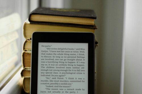 Książki a minimalizm – czytnik ebooków Kindle na tle papierowych książek