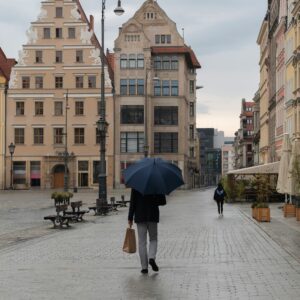 Mężczyzna idący jesienną ulicą z parasolem — spokojna scena w mieście, symbol dbania o zdrowie mężczyzn i akcji Movember