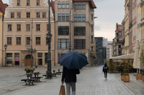 Mężczyzna idący jesienną ulicą z parasolem — spokojna scena w mieście, symbol dbania o zdrowie mężczyzn i akcji Movember